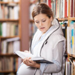 Pregnant women studying prenatal yoga training book